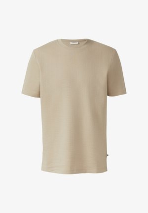 T-shirt beige clair à manches courtes et col rond, en tissu subtilement texturé, avec une petite étiquette de marque sur la couture latérale.