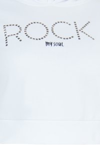 Vit sweatshirt med ordet "ROCK" i nitar i silverfärgade accenter och med "my soul" skrivet i svart handstil under. Slät textur, huva design.