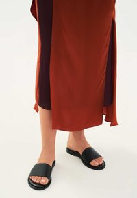 Črne natikače s širokim trakom, kombinirane z oranžno in bordo večbarvno tekočo krilo s stranskim razporkom. Gladek tekstura.