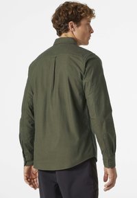 Camisa verde de manga larga con cuello abotonado, yugo trasero recto y puños con botón. Hecha de una tela texturizada con un corte relajado.