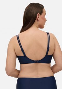Sujetador azul marino con tirantes dobles ajustables, tejido suave y un cierre de gancho y ojal en la parte posterior. Diseño minimalista sin patrones.