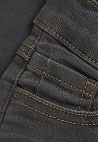 Tumehall denim kangas, millel on nähtavad heledast pruunist õmblused. Toad sisaldab väikest tagakotti tekstuuriga viimistlusega ja puhaste joontega.