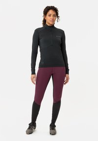 Svart langermet topp med halv-zip hals, parret med tettsittende burgunder og svarte leggings med sømdetaljer og slim fit.