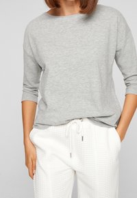 Gray long-sleeve top with a relaxed fit and soft texture, paired with white, textured drawstring pants featuring a quilted pattern.