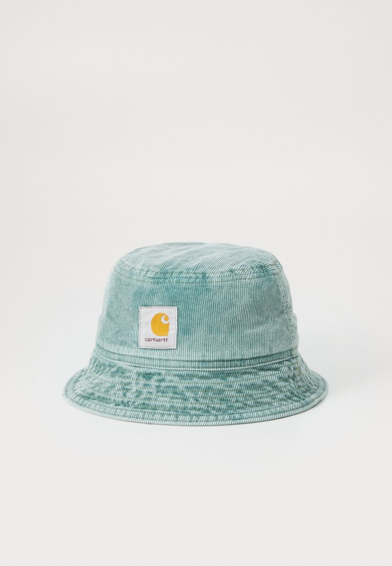 Mintgrøn samt buksedragt hat med bred skygge og et firkantet Carhartt mærke med et gult logo. Teksturflade med lodrette ribber.