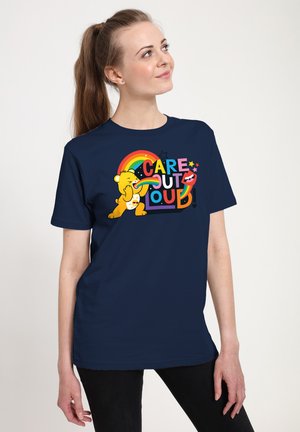 T-shirt bleu marine avec un design graphique coloré représentant un ours, un arc-en-ciel et le texte "CARE OUT LOUD" dans diverses couleurs et styles audacieux.