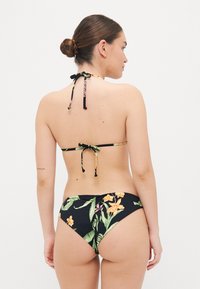 Bikini noir avec motif floral tropical, col halter avec liens ajustables, et bas taille basse. Texture lisse aux couleurs vives.