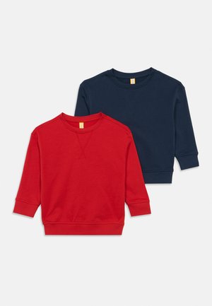 To lange langærmede crewneck sweatshirts med ribbede manchetter og nederkant, en rød og en navy, liggende fladt på en hvid baggrund.