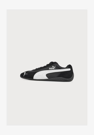 Baskets Puma noires à profil bas avec logo Puma blanc et bande sur le côté, semelle noire et lacets noirs, vues de profil.