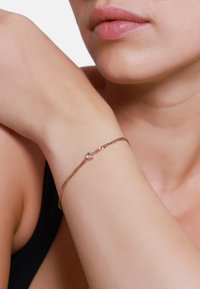 Verstellbares Armband aus roségoldener Kette mit einem zentralen Kristall. Die Kette hat ein zartes, strukturiertes Design, das ihre Eleganz unterstreicht.