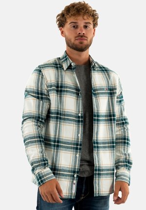 Geruite flanellen overhemd in blauw, groen en beige op een witte basis, lange mouwen, voorzakken en knoopsluiting. Draag het over een grijze t-shirt.