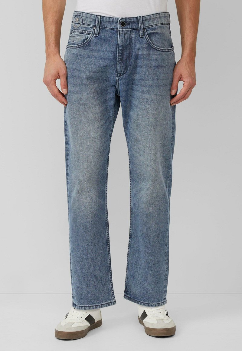 Jasnoniebieskie dżinsy z denimu o prostym kroju, z pięcioma kieszeniami, zapięciem na guziki z przodu i subtelnym blaknięciem, zestawione z białymi i szarymi tenisówkami.