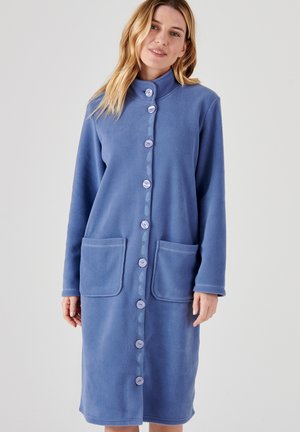 Garbamento in pile lungo e blu chiaro con colletto alto, chiusura frontale a bottoni, due tasche applicate e dettagli ricamati lungo la patta dei bottoni.