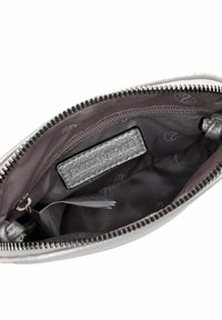 Interior view of a metallic silver zippered pouch showing a branded leather label and a small folded paper inside.