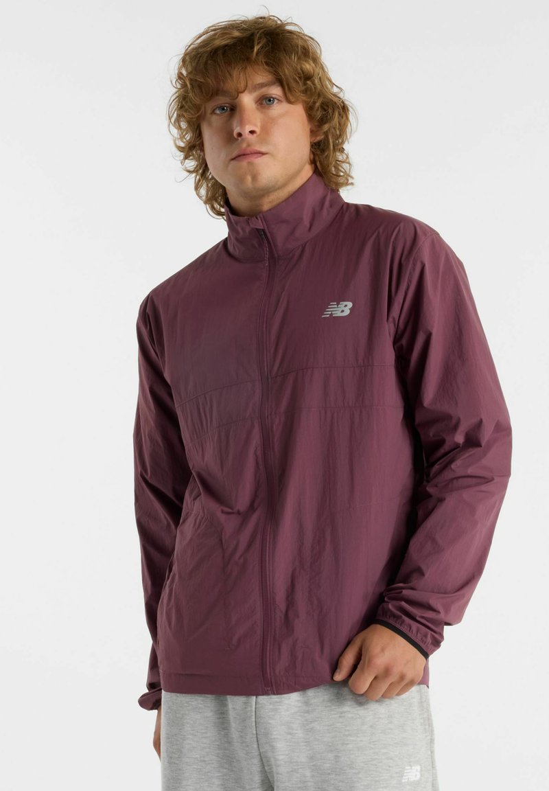 Lightweight, maroon windbreaker jacket with a high collar, zip closure, and a New Balance logo on the left chest. Smooth texture.