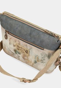 Borsa a tracolla beige e grigia con stampa floreale, tessuto testurizzato, chiusura con zip e tracolla regolabile con accessori decorativi.