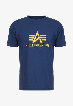 Mörkblå bomullströja med en gul screentryckt logotyp i geometrisk design och texten "ALPHA INDUSTRIES, KNOXVILLE, TENNESSEE, U.S.A."