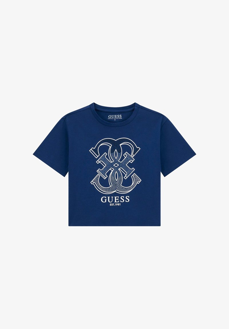 Krajša majica temno modre barve iz bombaža, z belo grafično zasnovo logotipa, ki vključuje prepletene črke in blagovno znamko "GUESS", ustanovljeno leta 1981.