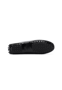 Chaussure plate en cuir noir avec une surface lisse, un bout arrondi et une semelle en caoutchouc flexible dotée de points de grip ronds pour une meilleure traction.