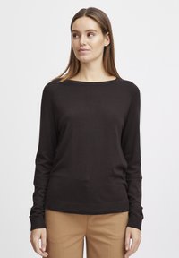 Pull marron foncé à manches longues avec un col ras du cou, fabriqué dans un matériau lisse et léger. Possède des poignets et un ourlet côtelés.
