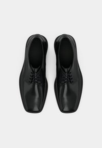 Chaussures en cuir noir avec une finition lisse, un bout carré et un système de laçage. Comprend six œillets et une semelle basse.
