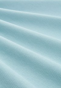 Jasnoniebieska teksturowana tkanina z wzorem w kratkę, charakteryzująca się miękkimi, pofalowanymi zagięciami, które podkreślają jej dotykowy wygląd.