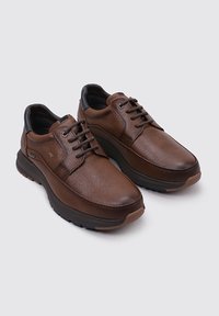 Zapatos de cuero marrón con un acabado texturizado, puntera redondeada y detalles en negro. Cuentan con un cierre de cordones y una suela acolchada para mayor comodidad.