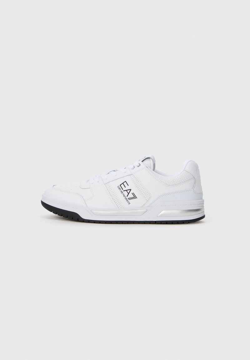 Hvite lave sneakers med svart såle og "EA7 Emporio Armani"-logo på siden, plassert mot en ensfarget lys bakgrunn.