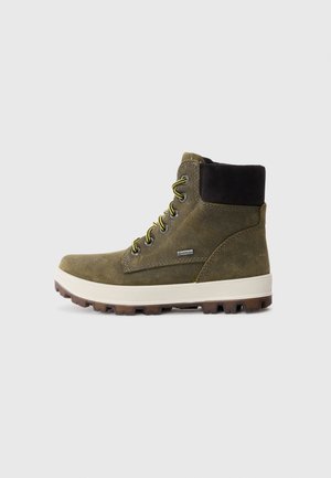 Botte haute en daim vert avec col rembourré noir, lacets jaunes, semelle intermédiaire blanche et semelle robuste marron, dotée d'une étiquette Gore-Tex sur le côté.