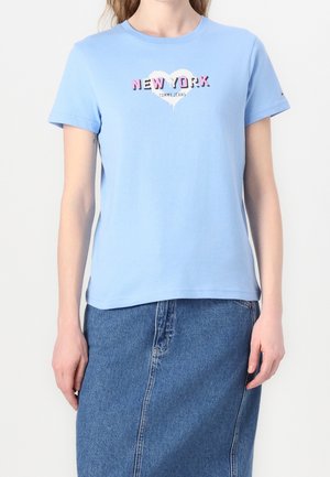 Lyseblå T-shirt med korte ærmer med teksten "New York" inde i et hvidt hjerte, kombineret med en blå denimsnørk.
