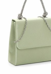 Sac à main en satin vert pâle avec fermeture à rabat, bandoulière chaîne argentée et deux poignées nouées ornées de strass.