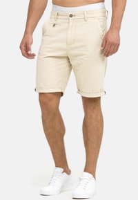 Beige denim shorts met omgeslagen uiteinden, voorzien van een zichtbare knoop en ritssluiting, zijzakken en een merkband in de taille.