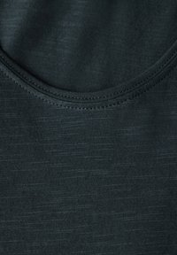 Tmavě zelený bezrukávový top s kulatým výstřihem, který má hladkou texturu a jemné variace v tónu látky.