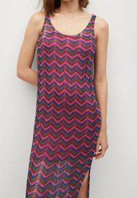 Robes sans manches arrivant au genou avec un motif zigzag multicolore en rose, vert et bleu. Présente une fente sur le côté. Fabriqué en tissu léger et texturé.