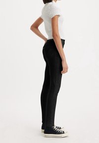 Svart denim skinny jeans med hög midja, med en standard fem-fickdesign och diskret sömnad på bakfickorna.