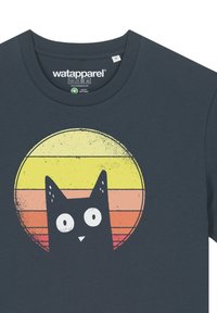 T-shirt en coton bleu marine mettant en avant un graphique d'un chat noir contre un fond de coucher de soleil jaune et orange avec un design circulaire texturé.