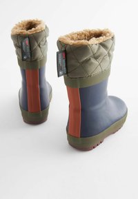 Bottes d'hiver isolées bleu et vert olive avec doublure en polaire beige et une bande rouge verticale à l'arrière, posées sur une surface blanche.