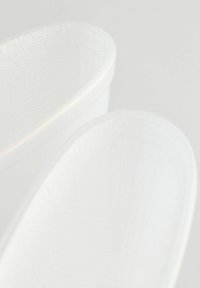 Bacs de rangement en tissu blanc avec une forme cylindrique lisse et une surface texturée subtile, présentant des bords arrondis et un design léger.