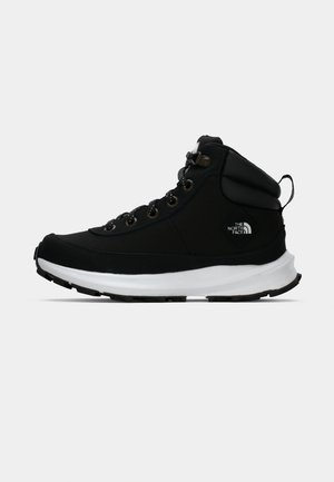 Black high-top sneakers with a padded collar, metal eyelets, and a white midsole. Features textured fabric and a prominent logo patch.