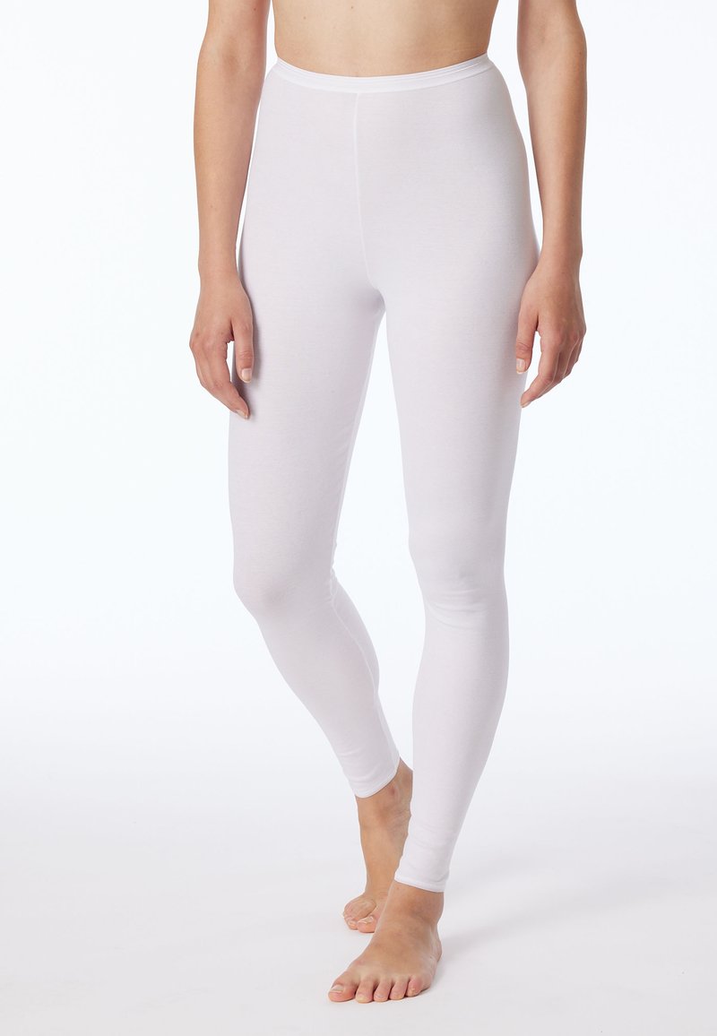 Leggings blancs en matériau lisse et extensible. Ils possèdent une taille haute et un design de jambe ajusté. Un modèle pieds nus se tient debout.