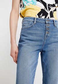 Lichtblauwe denim jeans met een hoge taille, een sluiting met vijf knopen en een klassiek zakontwerp, afgewerkt met een textuur.