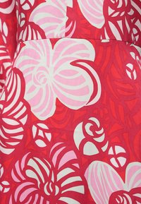 Roter Stoff mit großen weißen und pinkfarbenen Blumen sowie abstrakten Formen und Mustern, glatter Textur und lebendigem Farbkontrast.