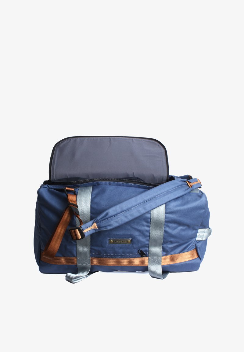 Blaue Stoff-Duffle-Tasche mit grauen Trägern und braunen Akzenten. Verfügt über einen Reißverschluss oben und eine strukturierte Oberfläche.