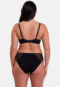 Ensemble de lingerie noire comprenant un soutien-gorge à dos en mesh et des culottes taille haute. Accents en dentelle détaillés sur les côtés, texture lisse, bretelles réglables.