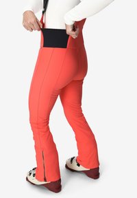 Rode skibroek met een elastische zwarte tailleband, slim fit ontwerp en ritsen bij de enkels, gemaakt van duurzaam, weerbestendig materiaal.