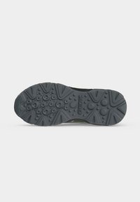 Semelle d'une chaussure Geox noire avec des motifs de bande de roulement circulaires et triangulaires et une surface texturée pour une meilleure traction.