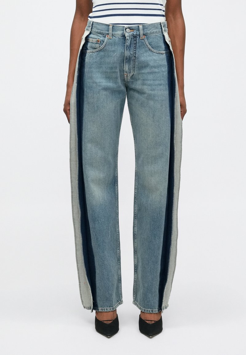 Denimi laiad jalad, erinevates sinistes toonides, kontrastsete külgpaneelidega, toorainetega servadega ning klassikalise viie tasku disainiga.