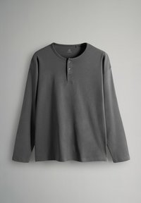Camisa henley de manga larga gris hecha de una tela suave, con cuello redondo, tapeta de tres botones y un ajuste relajado.