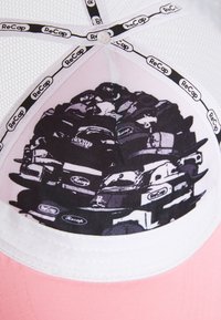 Beisballi kork, millel on roosa kangast äär ja valge võrkkate. Sees on must-valge graafika kuhjatust mütsidest ja "ReCap" siltidest.