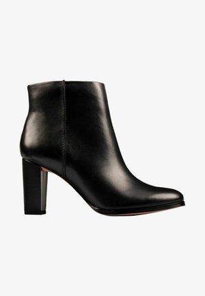 Černá kožená kotníková bota se čtvercovou špičkou a robustním blokovým podpatkem. Hladká textura, minimalistický design a elegantní silueta.